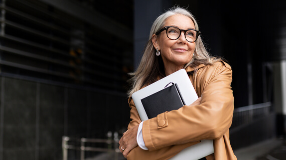 Senior businesswoman with a laptop in glasses outside the office