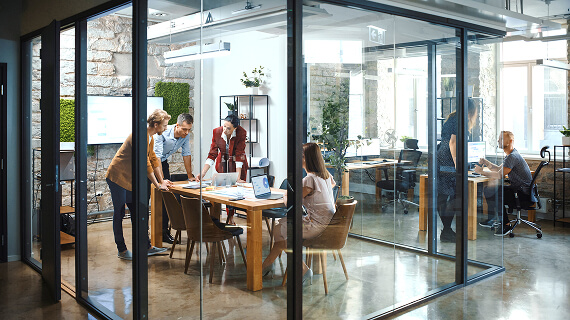 Interior of a modern office with a team meeting in glass conference room